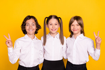 Sticker - Photo of three friendly schoolchildren show v-sign gesture wear white shirt isolated yellow color background