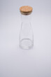 Vertical shot of a clear glass bottle with cork stopper isolated on a light gray background