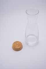 Sticker - Vertical shot of a clear glass bottle with cork stopper isolated on a light grabackground