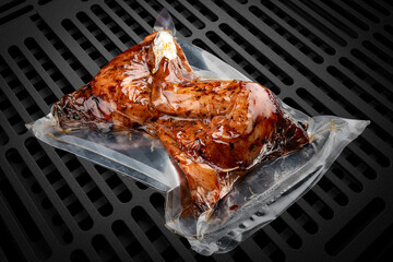 Vacuum-packed grilled meat, on a dark background, chicken thighs. Ready to eat.