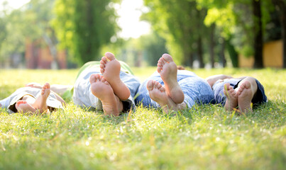 Family of four lying on the grass showing their feet to the camera