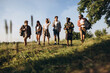 Group of friends, young men and women walking, strolling together during picnic in summer forest, meadow. Lifestyle, friendship,