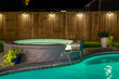 A backyard swimming pool and jacuzzi hot tob at night