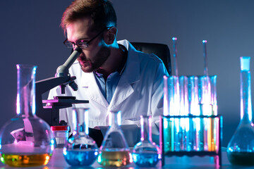 Poster - portrait of a laboratory technician at workplace. laboratory technician looks through a microscope. 