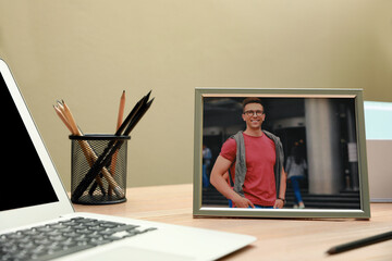 Canvas Print - Framed photo of happy young man near laptop on wooden table in office