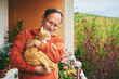 Portrait of middle age man holding cute ginger cat, resting on small cozy balcony