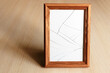 Cracked glass. Wooden frame for the picture. Light wood surface.