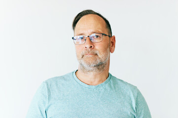 Close up portrait of middle age man wearing glasses and turquoise t-shirt, white background