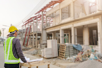 Wall Mural - young professional engineer in protective helmet and blueprints paper at the house building construction site