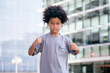 © jesus - Black boy, with afro hair, looking at the camera. Raising his fists, with a hard expression. With a office buildings background. Children, future, education and employment concept.