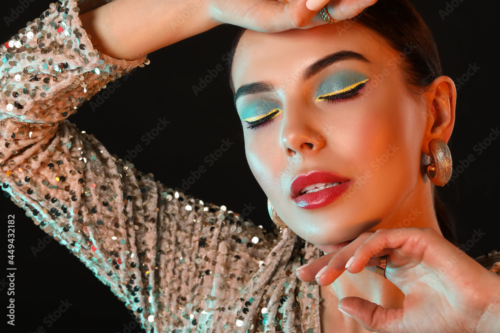 Beautiful young woman with stylish makeup on dark background
