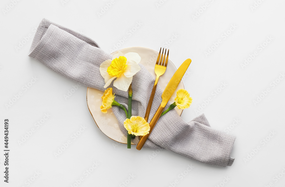 Beautiful table setting with narcissus flowers on white background
