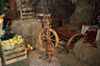 Vintage wooden spinning wheel with a spindle on the background of hay and a cart