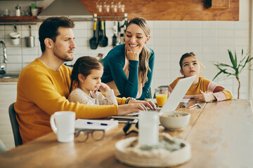 Wall Mural - Happy woman enjoys while spending time with her husband and daughters at home.