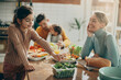 © Drazen - Small girl eats salad while having family lunch at dining table at home.