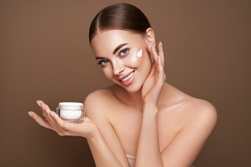 Wall Mural - beauty woman applying cream on her face. young woman with clean fresh skin. model with a jar of face