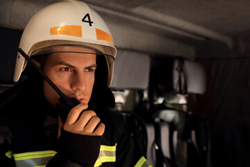 Wall Mural - Firefighter using portable radio set in fire truck, space for text