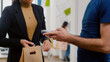 © DC Studio - Closeup of businesswoman paying food order having contactless payment with smart watch using POS terminal service. Delivery guy worker bringing takeaway food lunch order during lunchtime at workplace