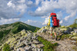 A male tourist with a large backpack climbs a mountain stone path high in the Carpathian Gorgan. Ukraine