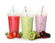 Different smoothies with straws in plastic cups and fresh fruits on white background