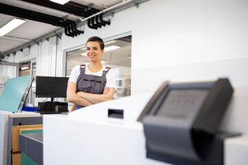 Wall Mural - Portrait of female print worker standing by computer to plate machine in print shop.