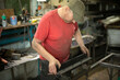 © Олег Копьёв - A guy in a red T-shirt works in a metal workshop.