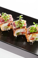 Sticker - Japanese sushi roll with japanese omelette - tamagoyaki. Sushi roll with avocado and cream cheese inside, topped with fried tuna. Delicious sushi roll with fish topped with sauce and fresh greens.