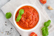 Traditional Italian marinara sauce in a bowl on a concrete background with spices and ingredients. Top view. Copy space.
