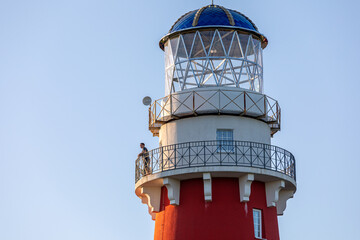 Lighthouse in red and white colors on the seashore, river bank or lake shore. Lighthouse hotel in a fishing village. Travel and tourism concept. Russia, Ryazan region, near the village Shumash.