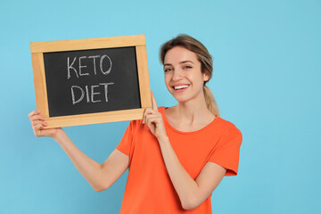 Wall Mural - Woman holding blackboard with phrase Keto Diet on light blue background