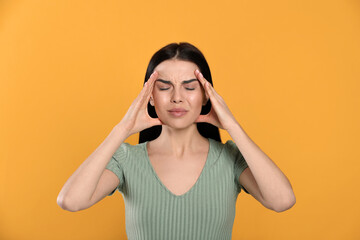 Wall Mural - Woman suffering from migraine on yellow background