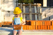 © Ольга Симонова - Little girl in a yellow hardhat is playing builder on the construction site of her future home. Expectation of moving, choosing a profession, children's education. Future profession, family business.