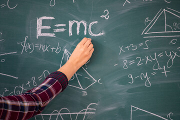 Teacher or student writing on blackboard during math lesson in school classroom
