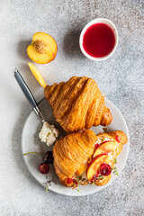 Wall Mural - Croissant with nectarine, cherry and ricotta cheese, gray stone background. Tasty breakfast. Top view.