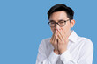 © whyframeshot - sick asian glasses male adult cold and flu symptom hand close mouth shut with stressful and tension white background health ideas concept