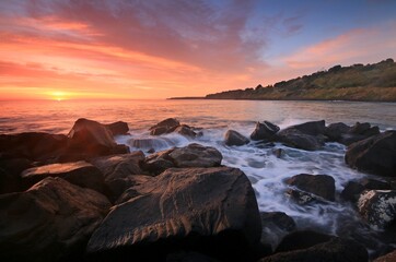 Wall Mural - a sunset over a body of water with a mountain in the background