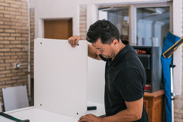 Wall Mural - Worker putting together pieces of furniture in a workshop