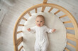 Top view portrait of cute little Caucasian baby infant kid child lying in children bassinet at home. Small newborn son or daughter relax in cradle after day sleep nap. Parenthood, childcare concept.