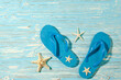 canvas print picture - blue beach rubber flip flops and starfish on a blue wooden background, view from above