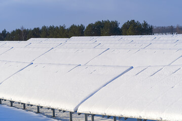 Solar panel field covered with snow. renewable energy in winter low efficiency. renewable green energy industry concept in winter time. photovoltaic solar modules in winter covered by snow