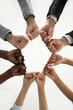 © fizkes - Close up crop vertical image of diverse multiethnic people join fists hands in circle show unity. Multiracial employees or friends involved in teambuilding activity. Teamwork, diversity concept.