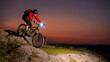 Cyclist Riding the Mountain Bike on Rocky Trail at Night. Extreme Sport and Enduro Biking Concept.