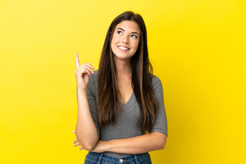 Young Brazilian woman isolated on yellow background pointing up a great idea