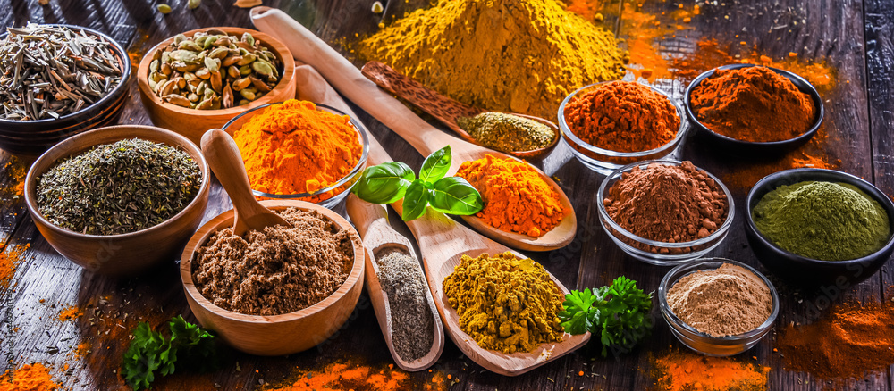 Variety of spices on wooden kitchen table. - obrazy, fototapety, plakaty 