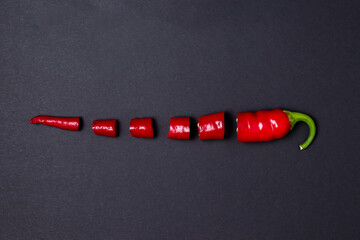 Canvas Print - Sliced red hot chili peppers on a black background. Chili pepper isolated