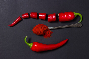 Canvas Print - Red ground pepper next to a whole red hot pepper on a black background. Chili pepper isolated