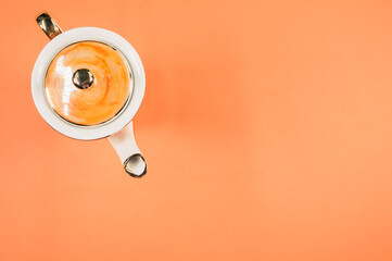 Sticker - Top view of an orange covered ceramic teapot on an orange isolated background with free space