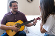 © Irene Castro Moreno - Young and attractive guy playing a romantic song in the guitar to his girlfriend while enjoying a day at home. Woman is surprised and happy listening to his song.
