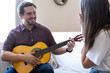 © Irene Castro Moreno - Young and attractive guy playing a romantic song in the guitar to his girlfriend while enjoying a day at home. Woman is surprised and happy listening to his song.