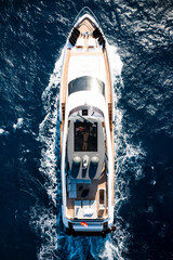 Wall Mural - View from above, stunning aerial view of a luxury yacht cruising on a blue water creating a wake. Costa Smeralda, Sardinia, Italy.